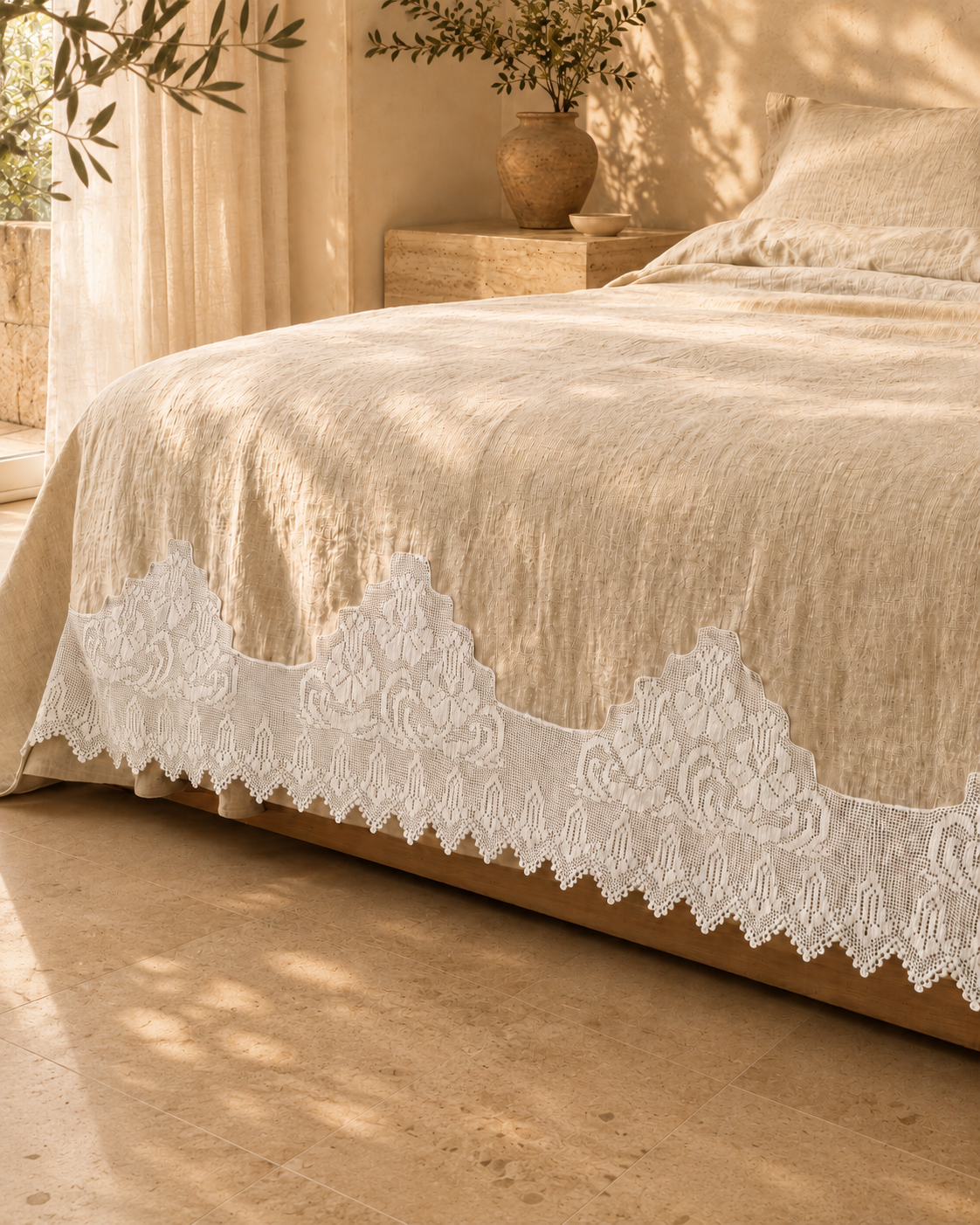 White handmade crochet lace edging styled along the lower edge of a warm neutral bed textile, showing its stepped floral design.