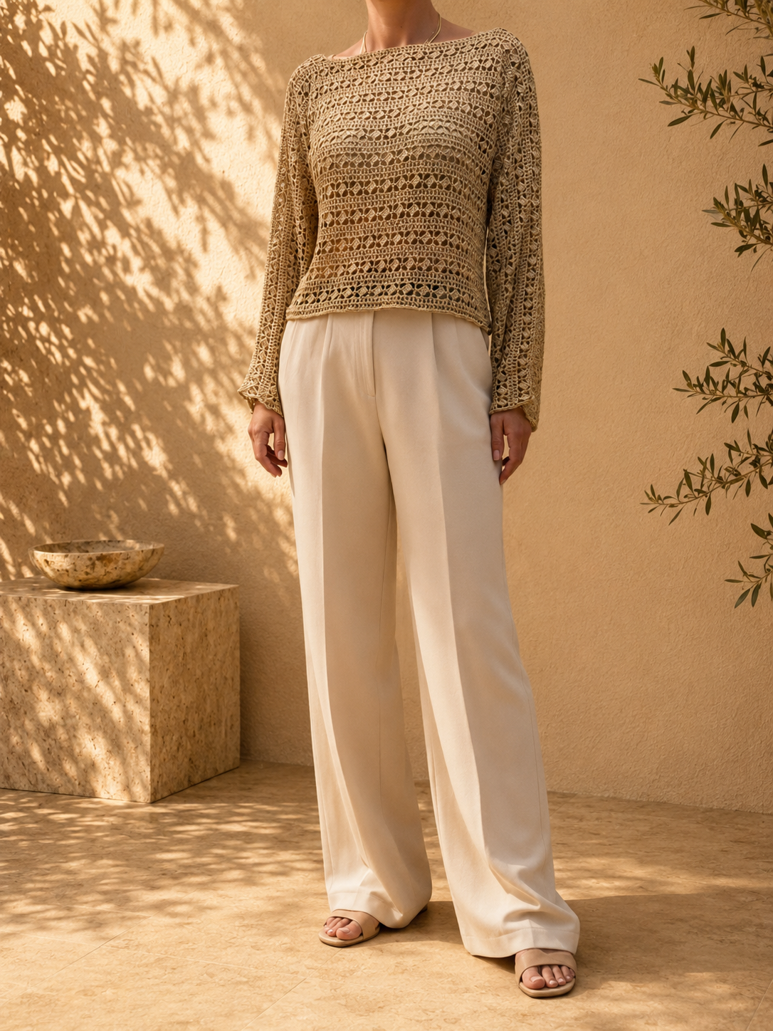 Front view of the sand-beige crochet blouse showing its waist-length body, straight shoulder line and repeating openwork rows.