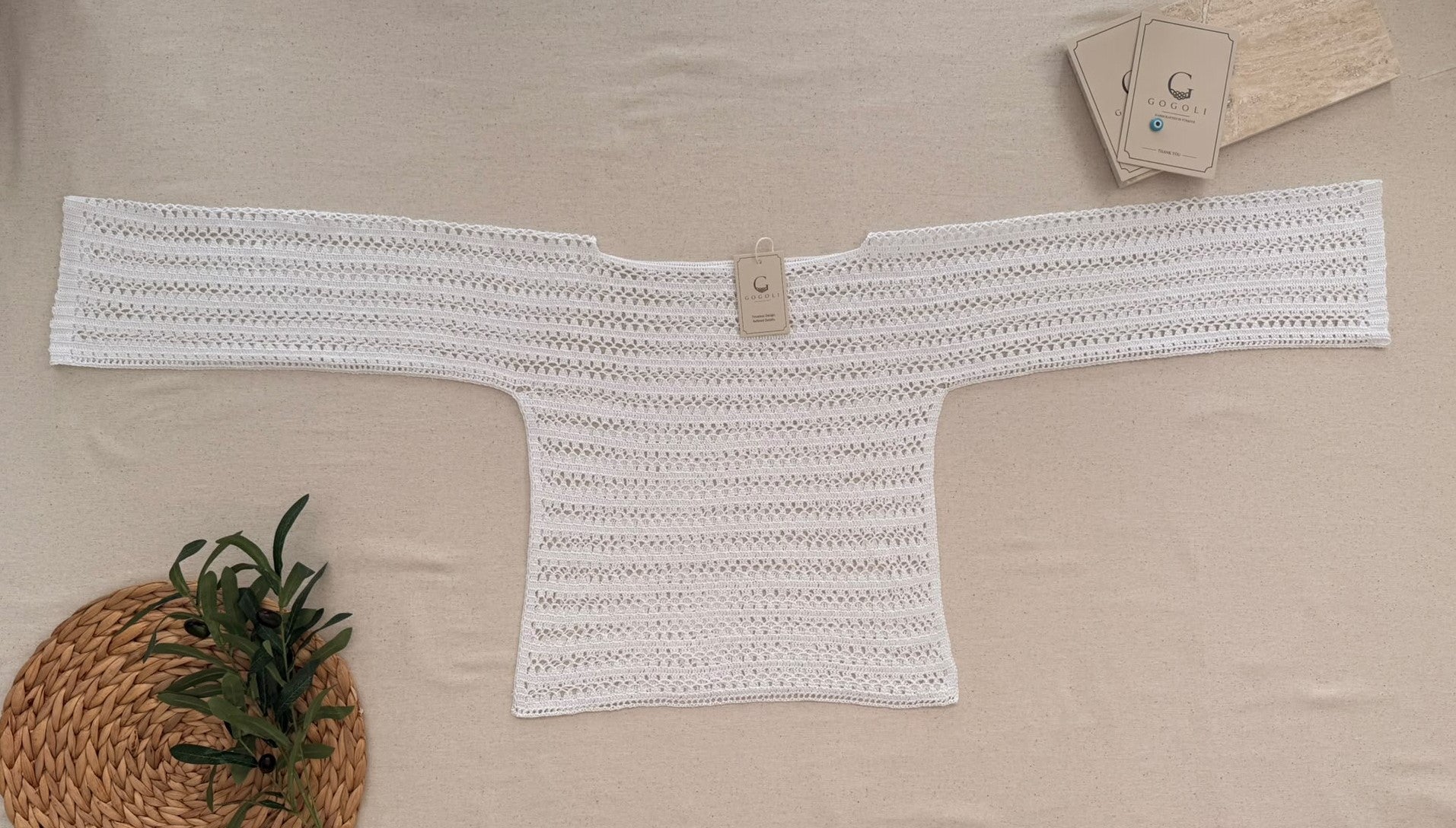 Flat-lay view of the long-sleeve white crochet blouse showing its wide neckline, straight sleeves and overall proportions.