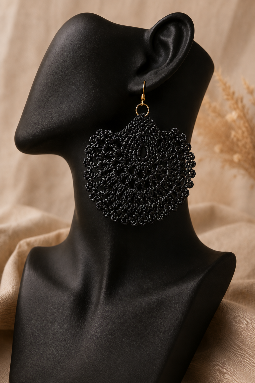 Black round crochet statement earring displayed on a black jewellery bust with a gold-tone stainless steel hook.