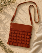 Flat-lay view of the handmade cognac crossbody bag with its adjustable leather strap fully visible.