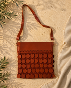 Front view of the handmade cognac brown crossbody bag showing five rows of leather sequins, leather top panel and long leather strap.