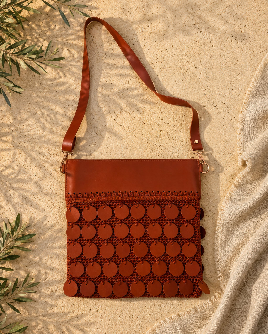 Front view of the handmade cognac brown crossbody bag showing five rows of leather sequins, leather top panel and long leather strap.