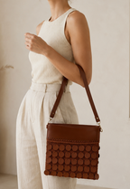 Side view of the handmade cognac brown crossbody bag worn over the shoulder, showing the leather strap and sequin-covered body.