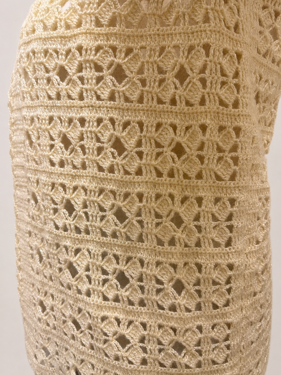 Detailed back view of the cream crochet vest showing its repeating openwork pattern and softly defined stitch texture