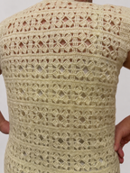 Detailed back view of the cream crochet vest showing its repeating openwork pattern and softly defined stitch texture.