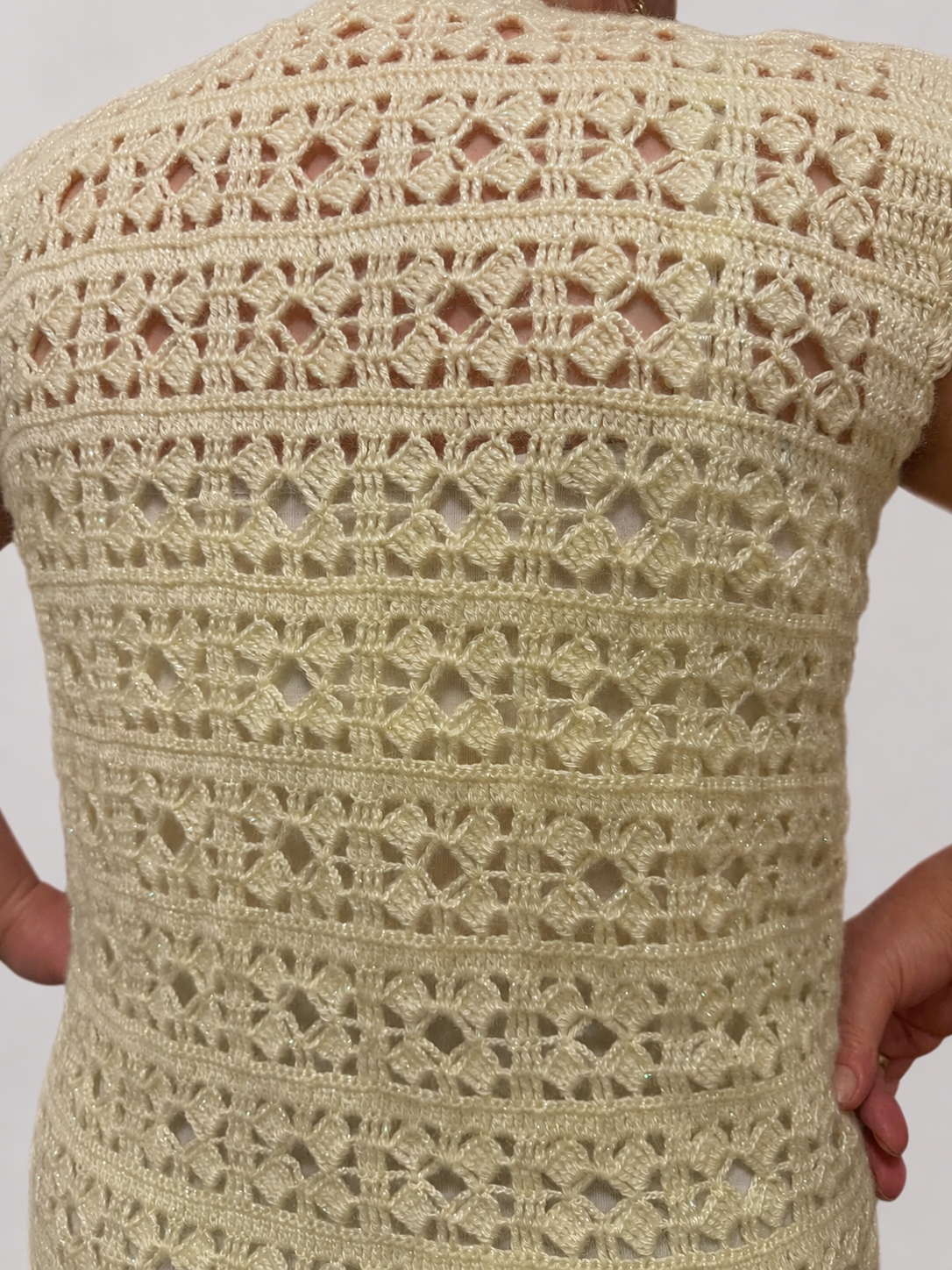 Detailed back view of the cream crochet vest showing its repeating openwork pattern and softly defined stitch texture.