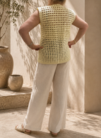 Back view of the handmade cream crochet vest showing its straight shoulder line, openwork texture and longline silhouette.