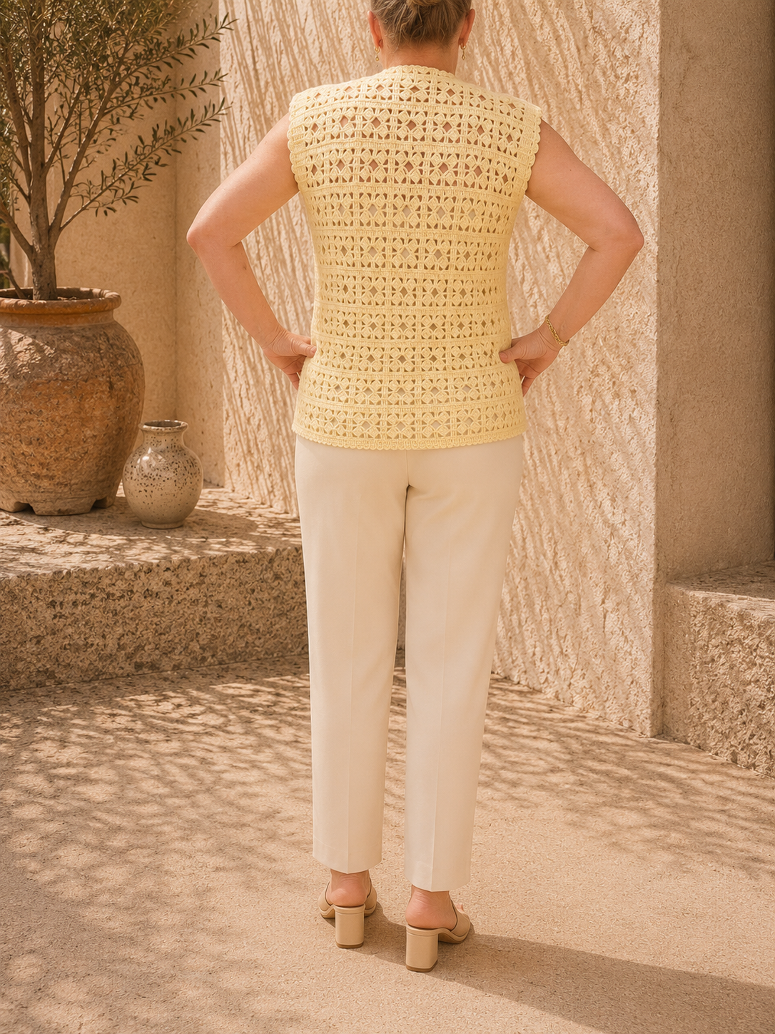 Back view of the handmade cream crochet vest showing its sleeveless construction and alternating openwork stitch bands.