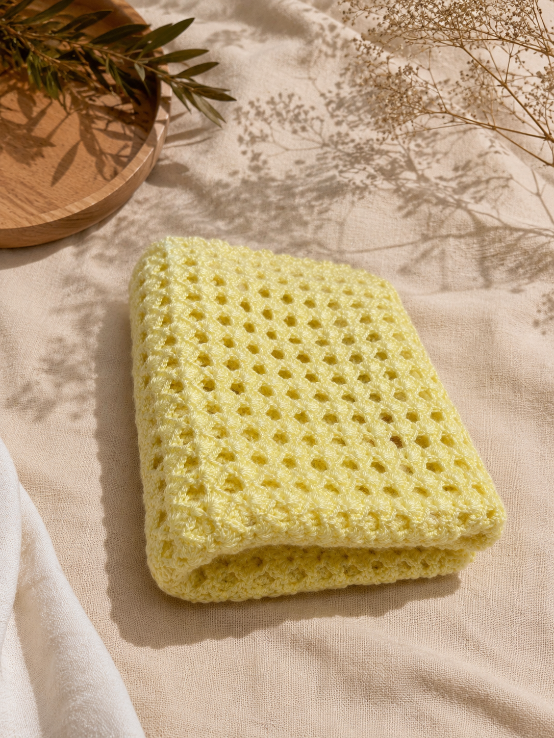 Folded view of the handmade cream crochet vest highlighting the smooth Alize Diva yarn and open stitch structure.