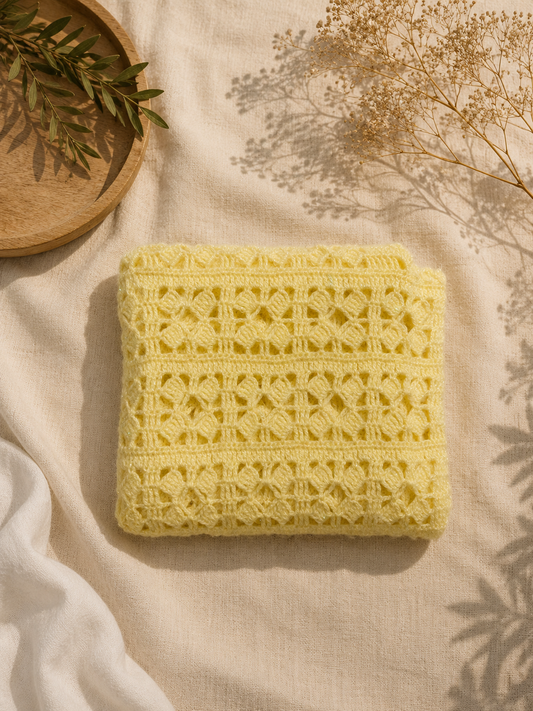 Folded view of the handmade cream crochet vest highlighting its decorative stitch bands and softly structured surface.