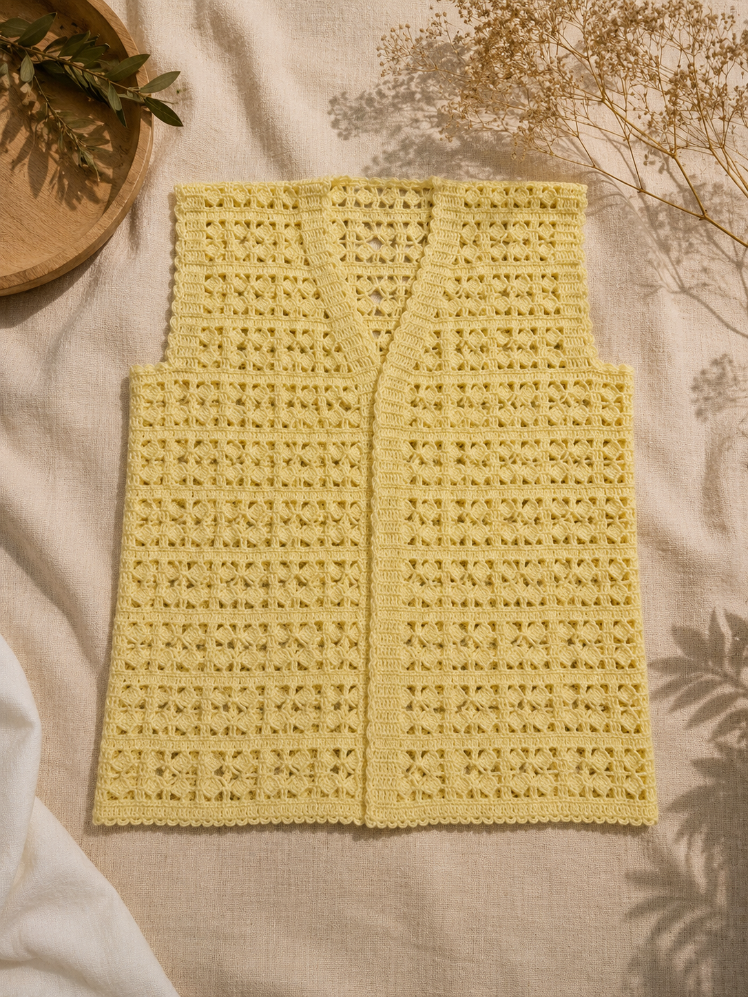 Flat-lay view of the cream crochet vest showing its V-shaped front opening, two front panels and textured openwork design.