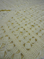 Close-up of the cream crochet vest showing its openwork panel construction and softly defined stitch pattern.