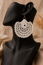 Cream round crochet statement earring displayed on a black jewellery bust with a gold-tone stainless steel hook.