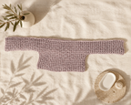 Dusty mauve long-sleeve crochet crop top laid flat with both sleeves extended on a light textile background.