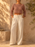 Handmade dusty mauve long-sleeve openwork crochet crop top styled with white wide-leg trousers.