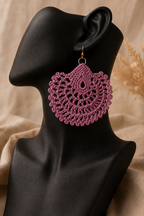 Dusty rose round crochet statement earring displayed on a black jewellery bust with a gold-tone stainless steel hook.