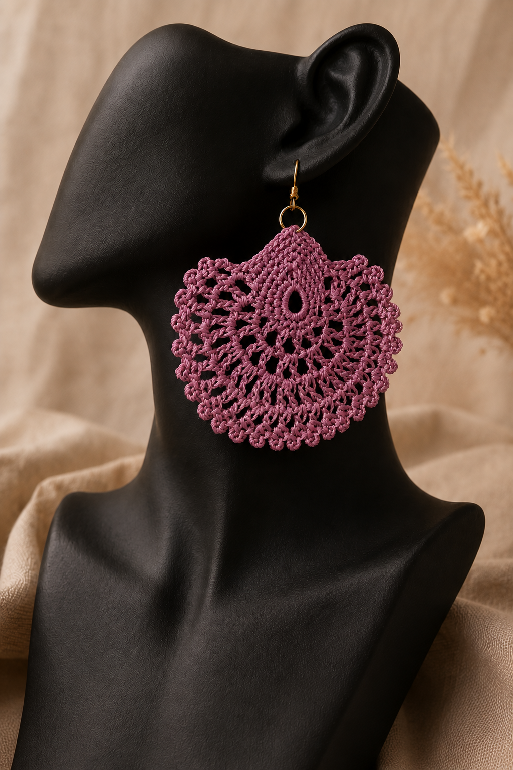 Dusty rose round crochet statement earring displayed on a black jewellery bust with a gold-tone stainless steel hook.