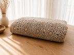Folded view of the handmade ecru crochet tablecloth showing the layered floral motifs and fine cotton openwork.
