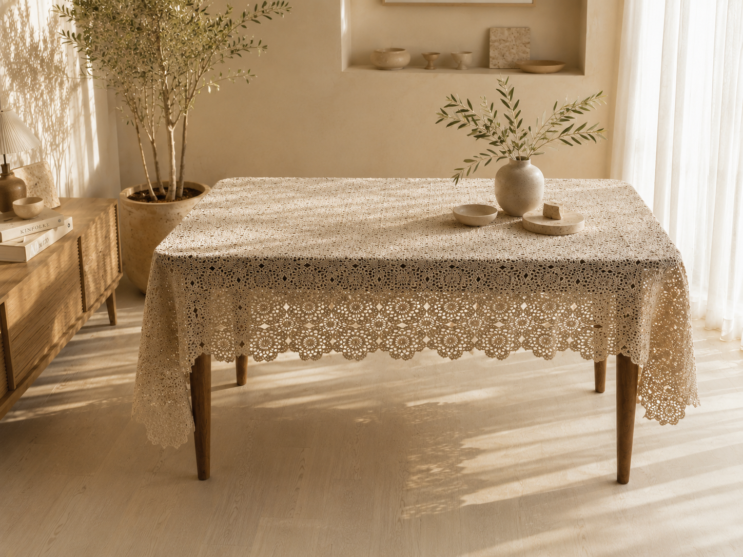 Large handmade ecru crochet tablecloth displayed on a rectangular dining table, showing its floral motif surface and draped edges.