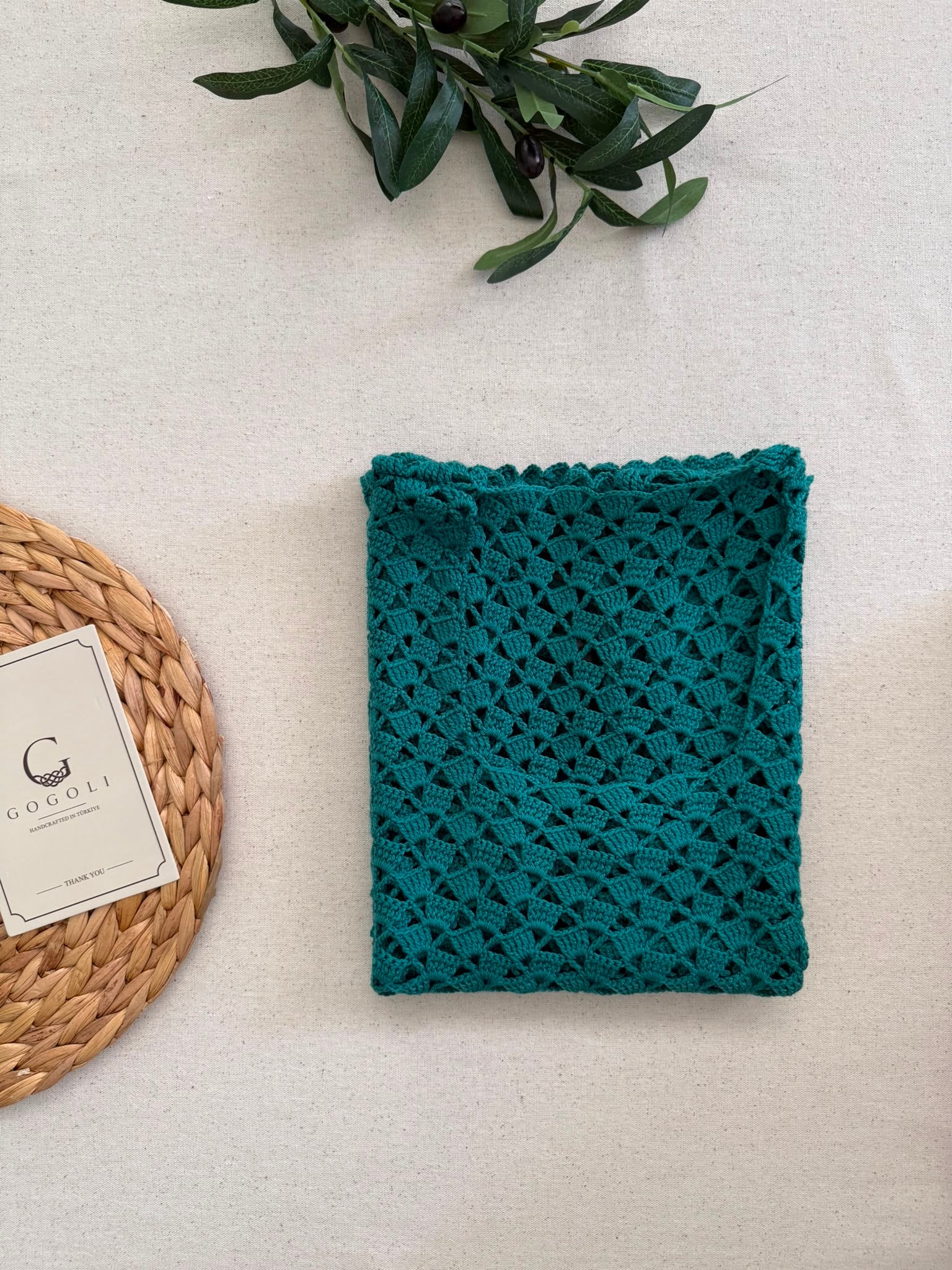 Folded view of the emerald green crochet top showing its scoop neckline, openwork texture and decorative edge finish.