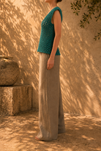 Three-quarter side view of the emerald green crochet blouse highlighting its relaxed body and gently widening hem.