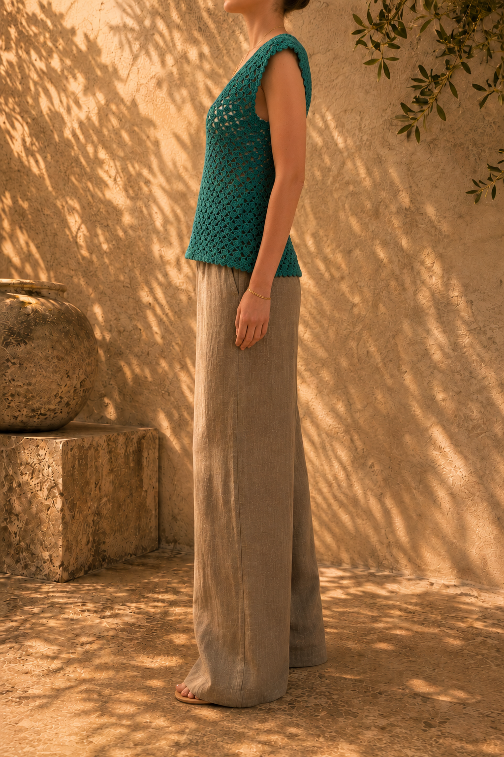 Three-quarter side view of the emerald green crochet blouse highlighting its relaxed body and gently widening hem.
