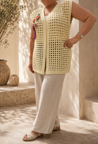 Front angled view of the cream crochet vest showing the floral shoulder appliqués, button closure and relaxed straight cut.