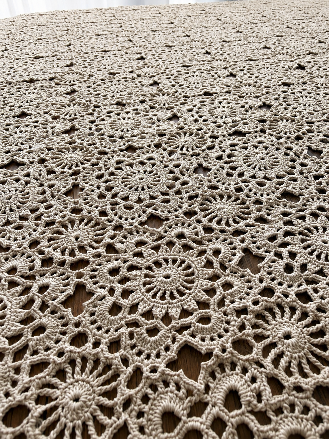 Close-up of the tablecloth surface showing hand-crocheted floral motifs, open joining spaces and mercerized cotton texture.