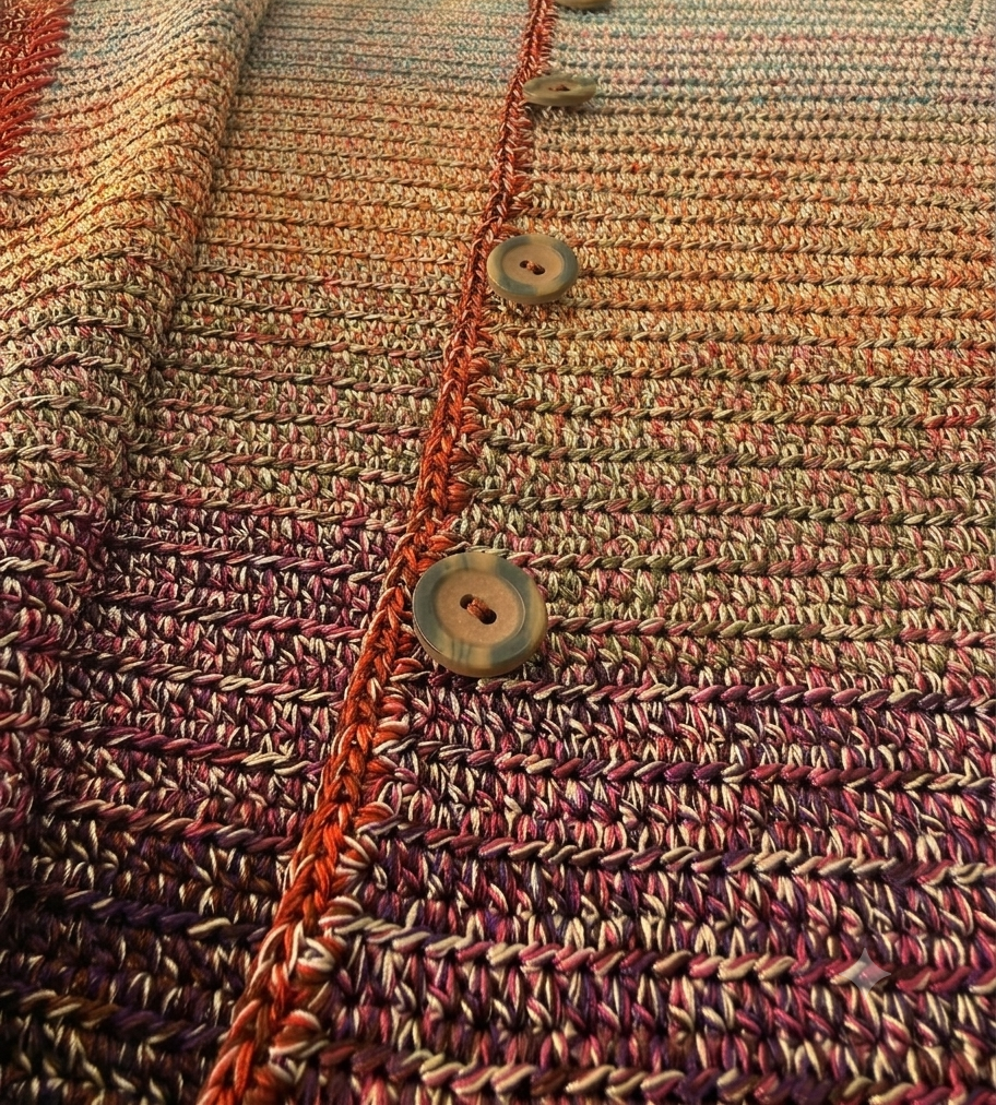 Close-up of a functional button, contrasting front placket and densely worked single crochet texture.