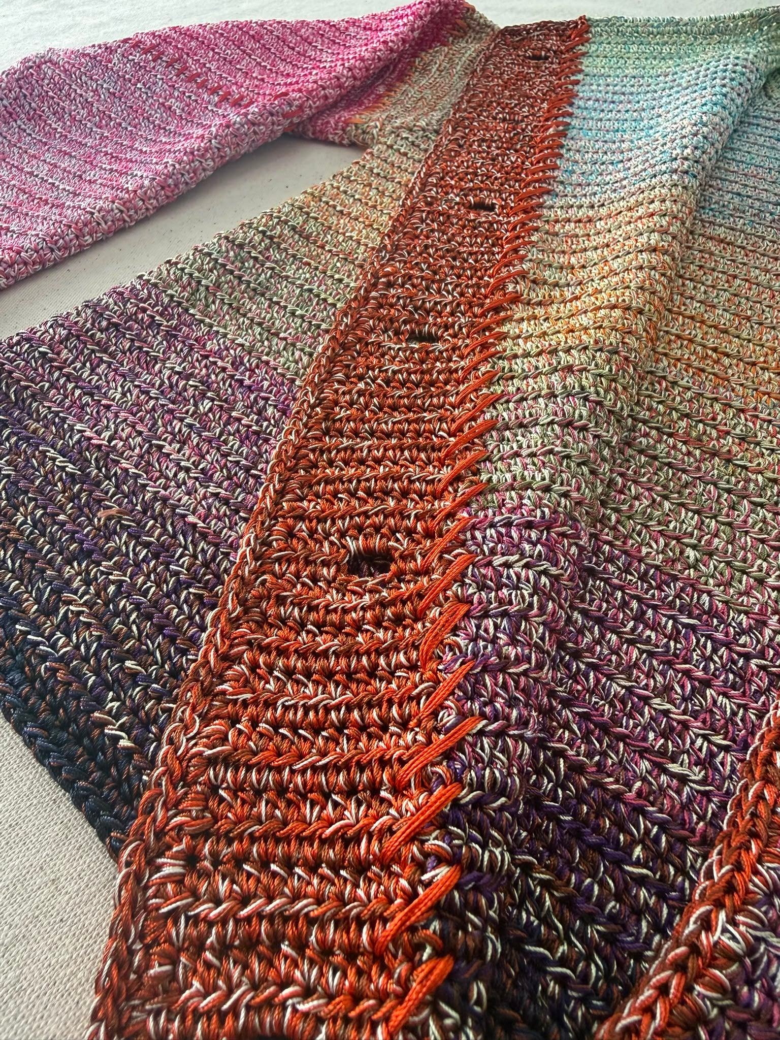 Detailed view of the openwork front placket worked in warm tones against the dense five-strand crochet body.