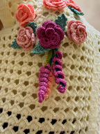 Detailed view of the three-dimensional crochet flowers and leaves individually made and attached by hand.