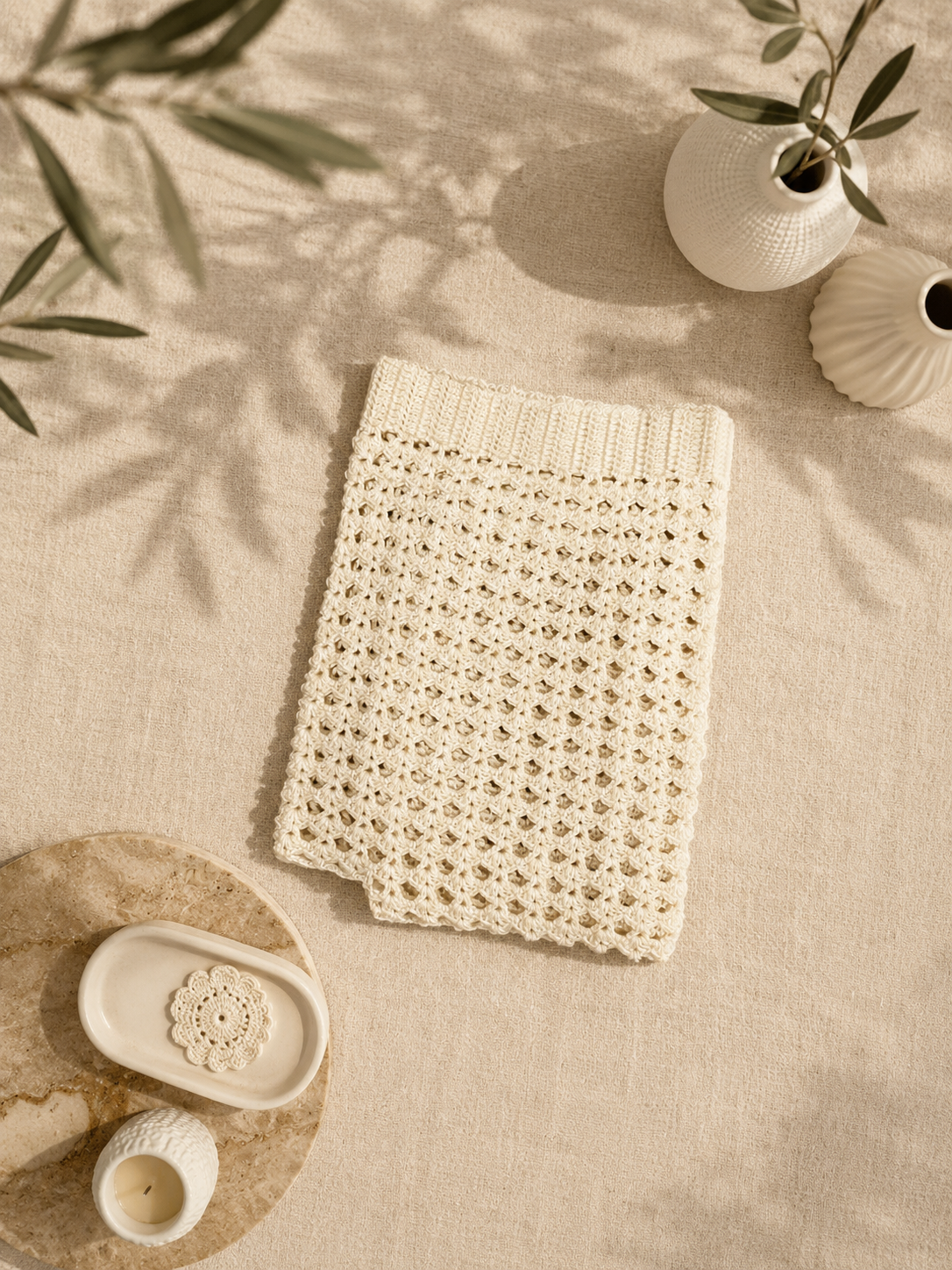 Overhead view of the handmade ivory crochet tank top arranged on a light surface with neutral accessories.