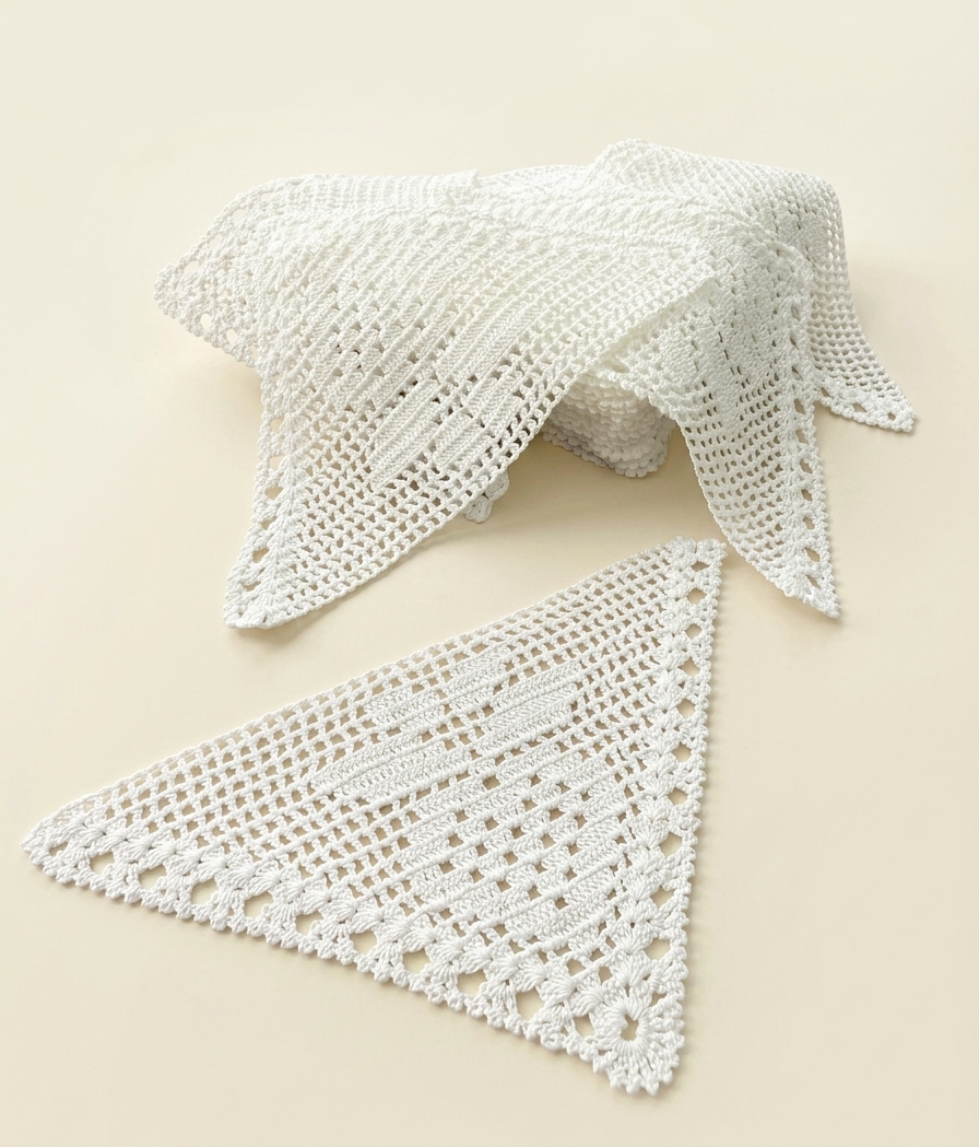 Several handmade white triangular crochet lace motifs arranged together on a light background.