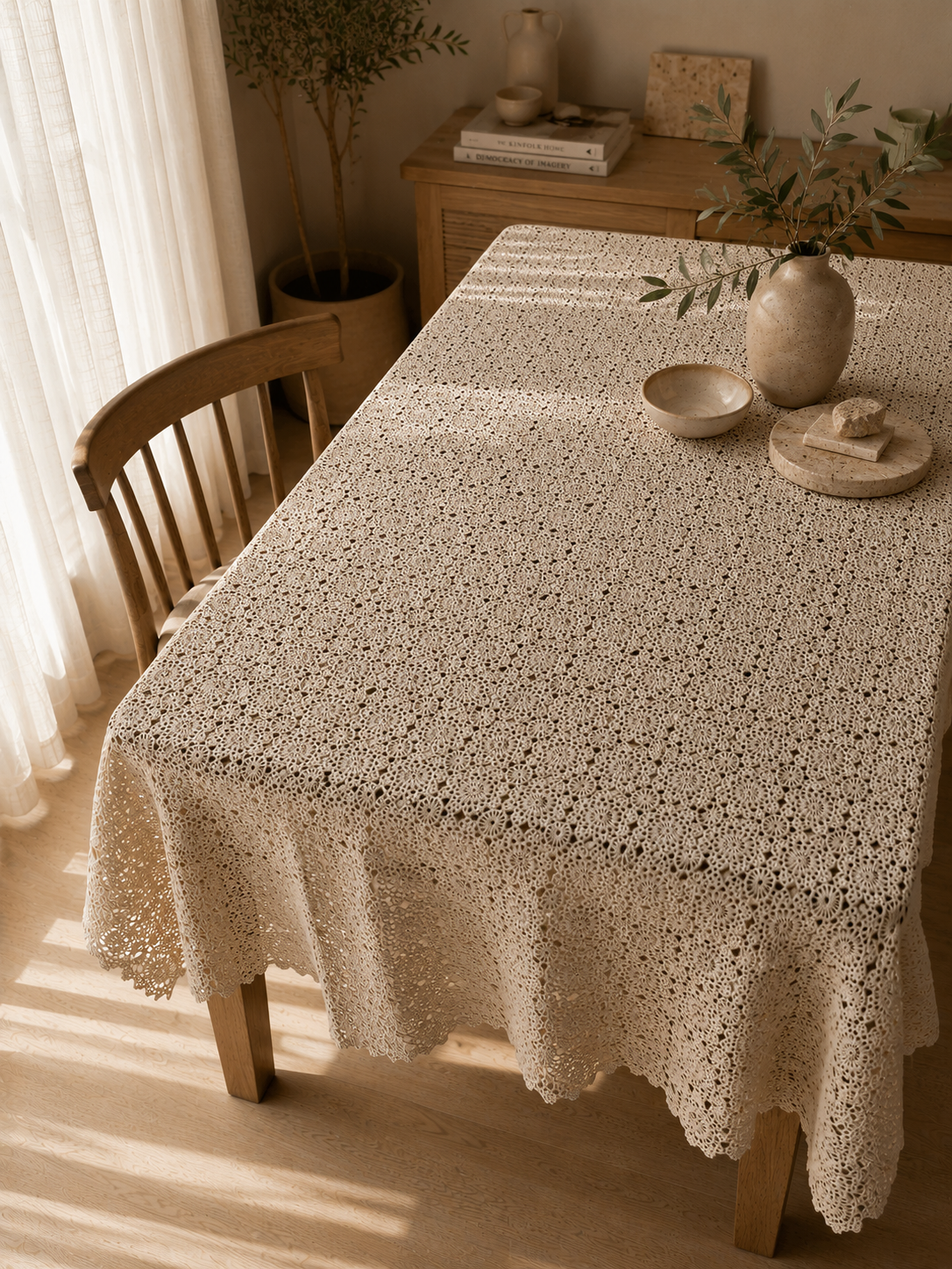 Angled view of the ecru crochet tablecloth arranged across a wooden dining table with its floral motifs clearly visible.