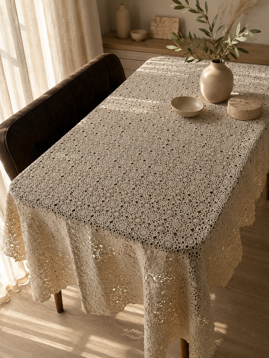 Large ecru floral motif crochet tablecloth styled on a dark wooden dining table in a warm interior.