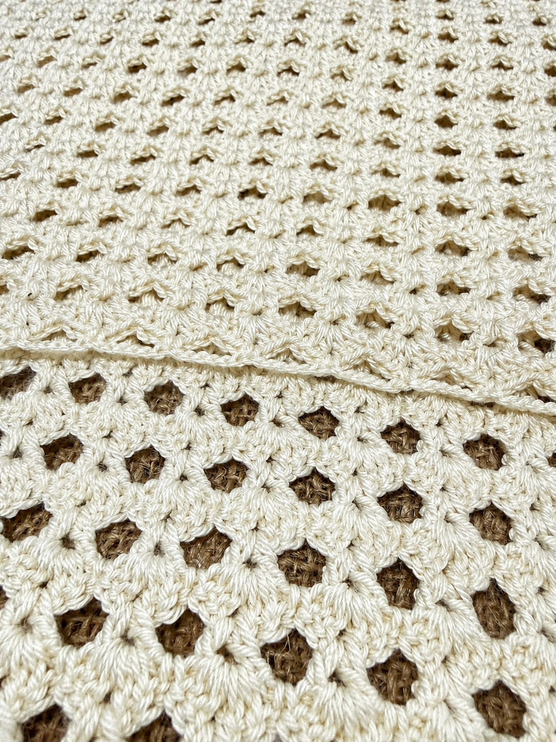 Close-up of the ivory crochet tank top showing the transition from close-set stitches to decorative openwork.