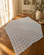 Large 80 cm square white crochet table topper displayed on a wooden table, showing its nineteen-by-nineteen floral motif arrangement.