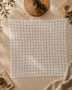 Overhead view of the large square white crochet table topper showing its regular twenty-by-twenty motif grid.