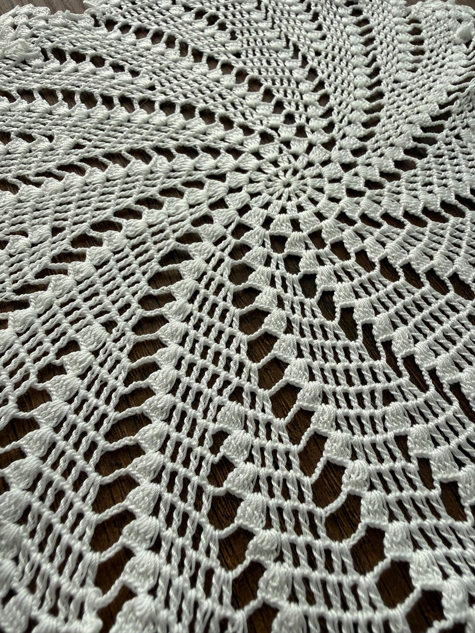 Close-up of the central openwork structure of the round lace motif made from white mercerized cotton thread.