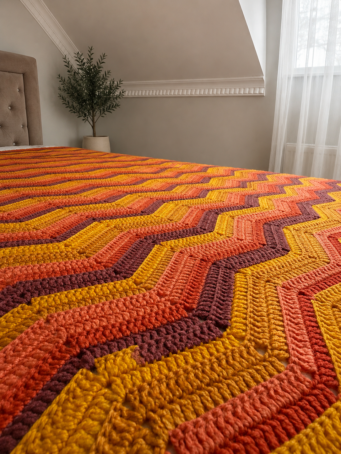 Close view of the multicolour chevron blanket draped across a bed, showing its soft texture and flowing pattern.