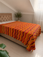 Angled view of the large chevron crochet blanket draped naturally over the side and foot of a bed.