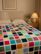 Closer view of the colourful square crochet motifs and cream joining lines across the bed.
