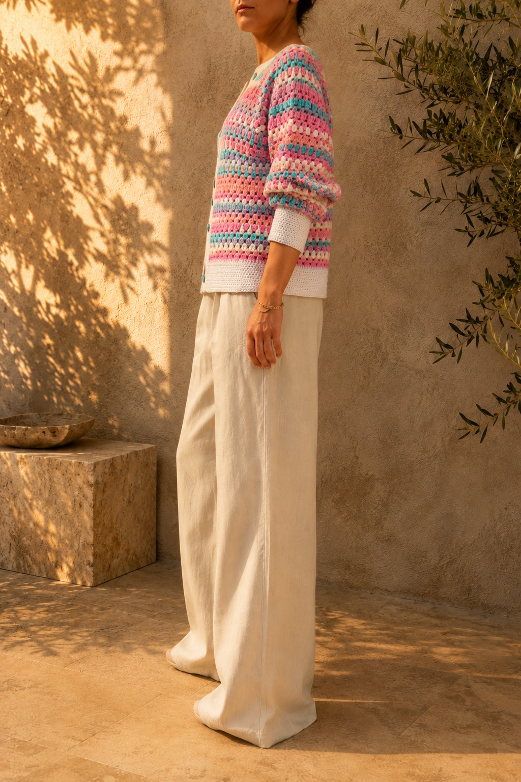Three-quarter view of the handmade multicolour crochet cardigan highlighting its button front, long sleeves and white ribbed cuffs.