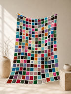 Full-length view of the handmade multicolour crochet blanket with rows of hand-joined square motifs.