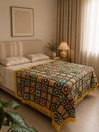 Large handmade multicolour floral motif crochet blanket displayed across a bed with contrasting dark joins and yellow borders.