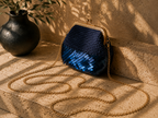 Angled view of the navy handmade crochet evening bag highlighting the partial sequin surface, rounded body and chain strap.