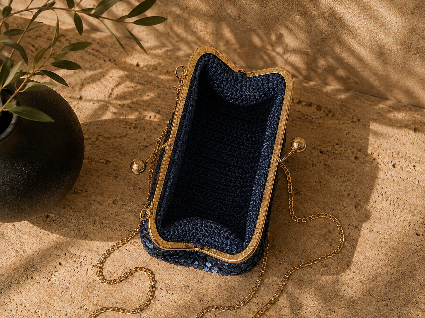 Open view of the navy handmade crochet evening bag showing the unlined interior and rose gold-tone kiss-lock frame.