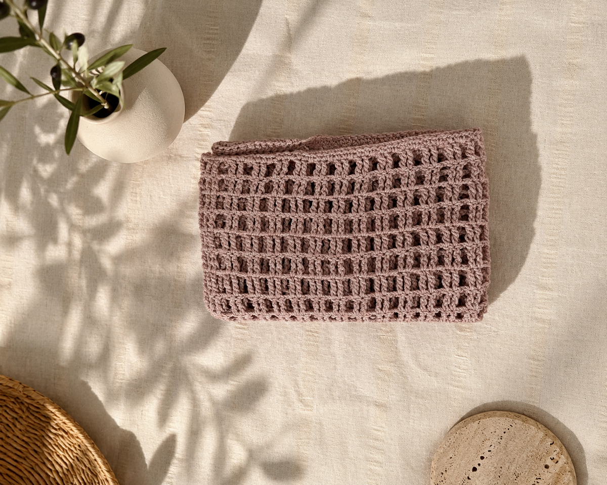 Folded dusty mauve crochet crop top showing the airy square-based openwork texture.