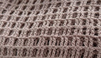 Close-up of the square openwork crochet stitches worked in dusty mauve KnitMe Vegan acrylic yarn.